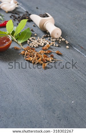 fresh and dried chili fruits, peppercorn, pepper powder, sauce and garlic, bay leaves on old black wooden table background
