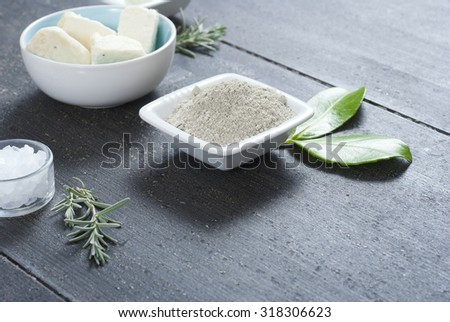 cosmetic clay powder, creams, shea butter and bath salt on old black wood table background