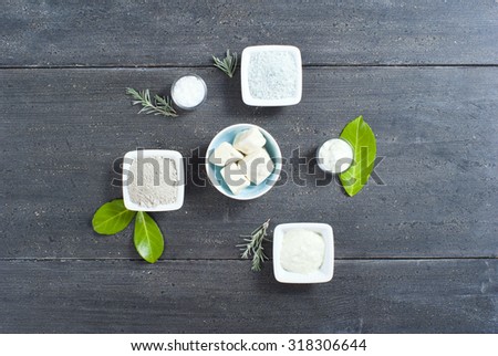 cosmetic clay powder, creams, shea butter and bath salt on old black wood table background