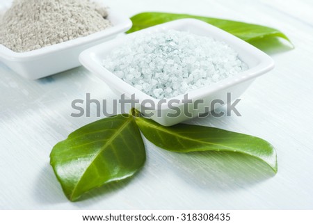 cosmetic clay and bath salt on white wooden table