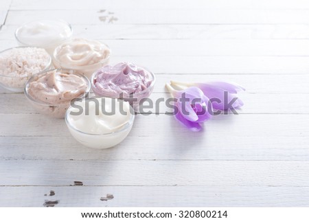 beauty product samples and autumn crocus herbal flower on white wooden table