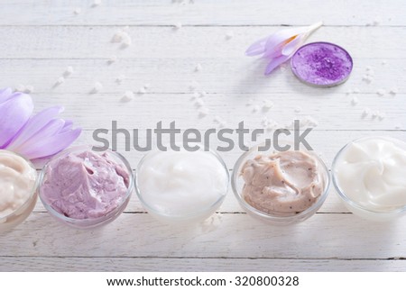 beauty product samples and autumn crocus herbal flower on white wooden table