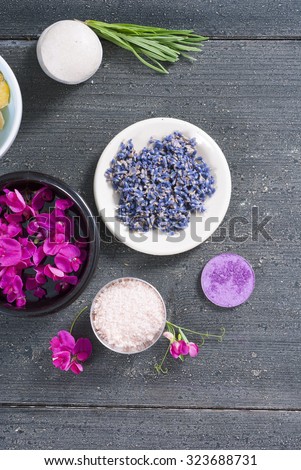 pink linaria flowers and bath salt, dried lavender buds on black wood table