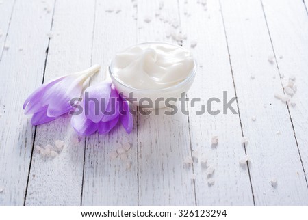 cosmetic cream and autumn crocus herbal flower on white wooden table