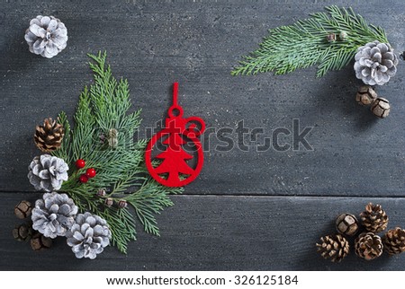 Christmas decoration background: red felt ornaments, pine and cypress cones with twigs on black wood table