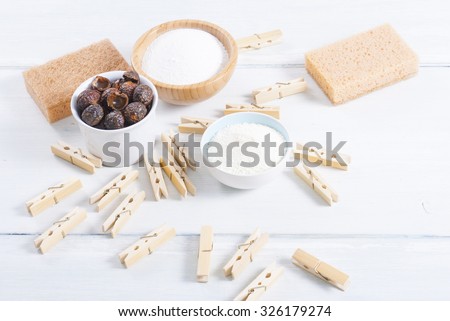 soap nuts, washing powder, clothing clips on white wooden surface