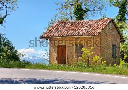 Small rural brick house near road among trees in Piedmont, Northern Italy.