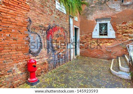 Small courtyard among old red brick walls with graffiti in Venice, Italy.