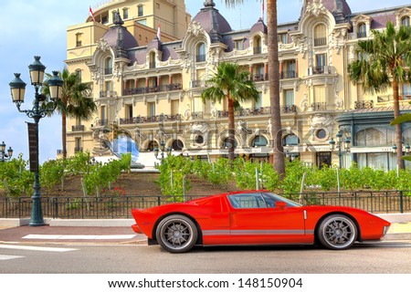 MONTE CARLO, MONACO - JULY 13: Red sports car and Hotel de Paris - luxury hotel opened in 1863, contains rooms and suites with exclusive city and sea views in Monte Carlo, Monaco on July 13, 2013.
