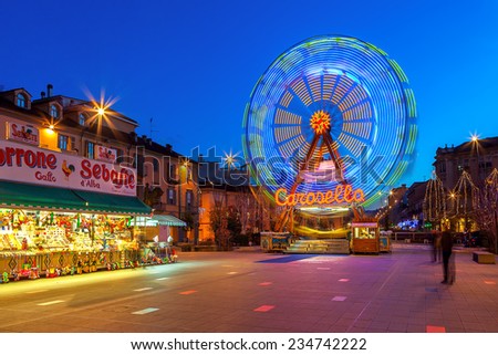 ALBA, ITALY - DECEMBER 30, 2013: Illuminated observation wheel and stall with sweets on town square as part of traditional Christmas and New Year celebrations.