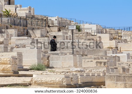 JERUSALEM, ISRAEL - JULY 13, 2014: Man prays on Jewish cemetery on Mount of Olives - most ancient and important cemetery where burials started 3,000 years ago with about 70,000 tombs. (Focus on man).