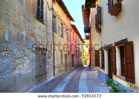 Narrow paved street among old abandoned house from one side and renovated from other in small town of Serralunga D\'Alba in Northern Italy.