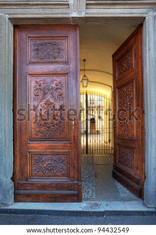 Vertical oriented image of beautiful ornate wooden door at the entrance to small courtyard in town of La Morra, Northern Italy.
