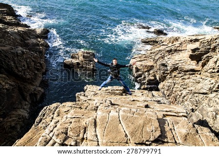 Happy man with jumping on the rocks near Atlantic ocean