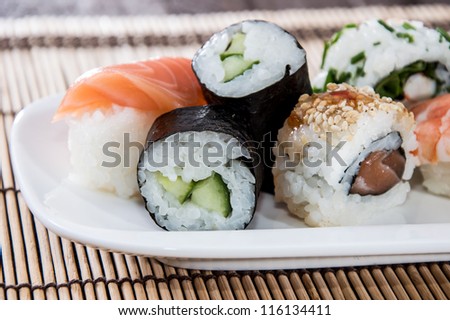 Mixed Sushi rolls on a plate with bamboo in the background