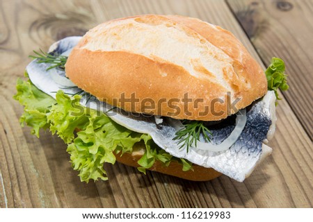 Fresh Herring on a roll against wooden background