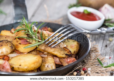 Skillet with fresh roasted Potatoes on vintage wooden background
