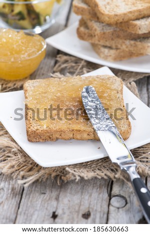 Bread with Pineapple Jam on a small plate (wooden background)