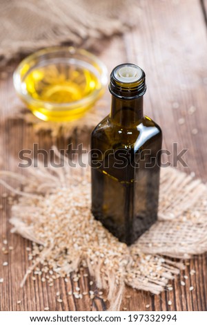 Small bottle with Sesame Oil and some Seeds on wooden background