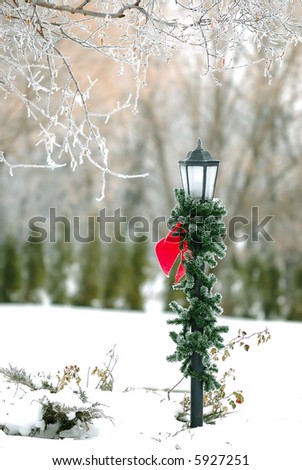 A white winters day, a Christmas decorated street lamp on residential driveway.