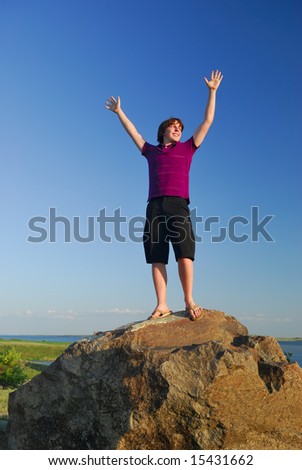A young man celebrates achievement in a nature setting.