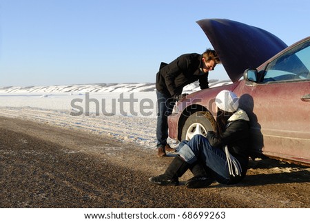 A couple are stranded at side of highway with a car breakdown in winter.