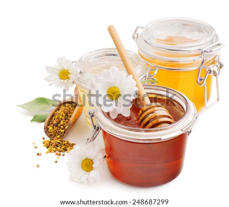 Honey in glass jars with flowers and pollen isolated on white background