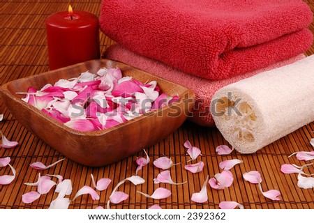 Towels, candle, carnation and rose petals, and bath sponge in a spa