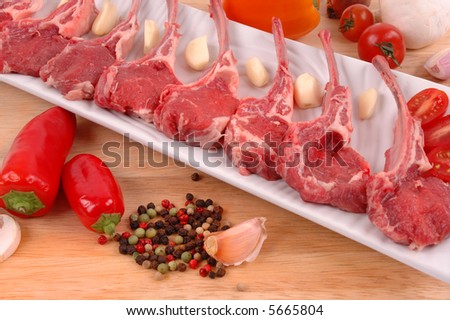 Lamb chops, pepper, mushroom, garlic, shallots, salt, and pepper on a wood board