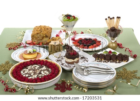 Elegant table with many desserts and fruits (eclair, pecan swirl cake, raspberry pie, rice pudding, cheese cake, creme caramel, and more)