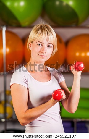 Woman workout with dumbbell in gym, biceps exercise closeup