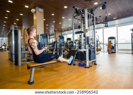 sport, fitness. lifestyle and people concept - young woman flexing muscles on gym machine