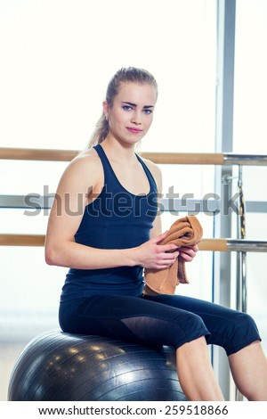 Beautiful young woman girl after physical excercise in fitness center gym  sitting on gymnastics ball.