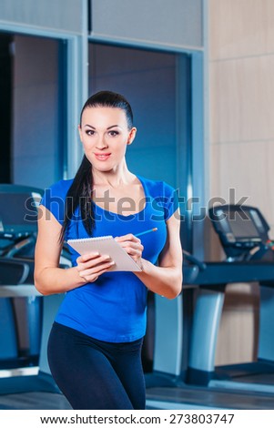 fitness, training, fitness, technology and lifestyle concept - Smiling woman with hands in bloktnotom