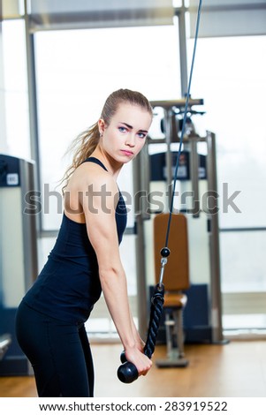 sport, fitness, lifestyle and people concept - young woman flexing muscles on gym machine