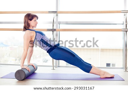 fitness, sport, training and lifestyle concept -  woman doing pilates on the floor with foam roller