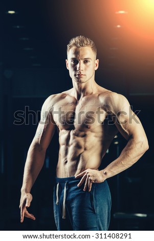 Silhouette of a strong athlete. Confident young fitness man with strong hands. Dramatic light