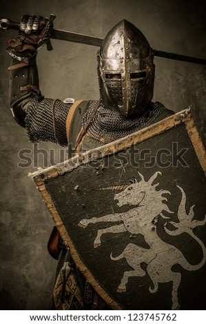 Medieval knight with sword and shield against stone wall