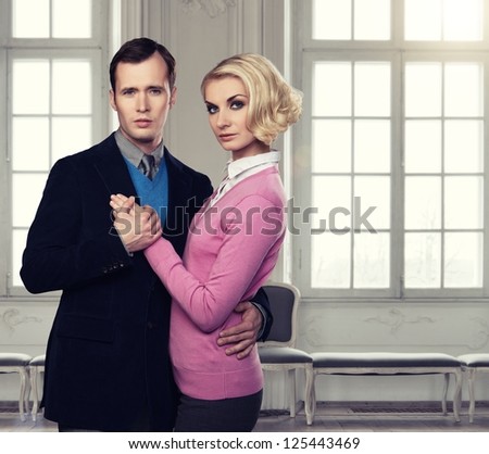 Elegant couple indoors standing near window