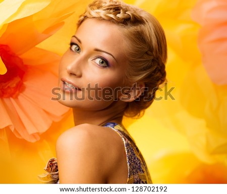 Beautiful young woman among big yellow flowers
