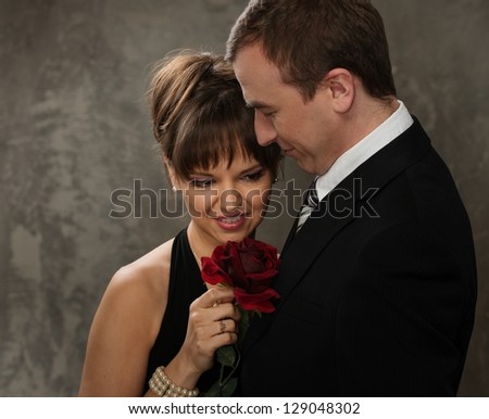 Young  man and woman with red rose in elegant evening dress