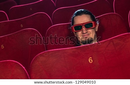 Funny young man in 3D glasses watching movie in cinema