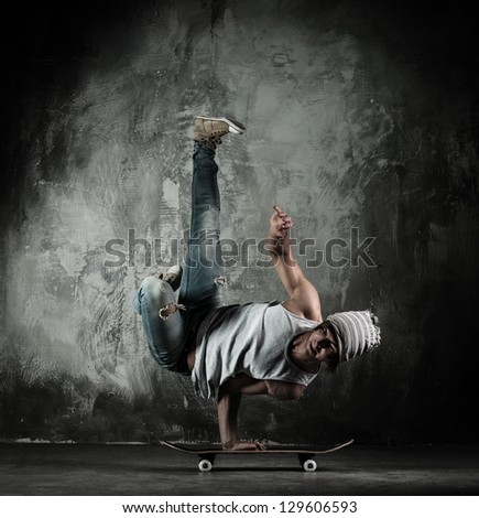 Young b-boy man doing brake dancing movements on skateboard