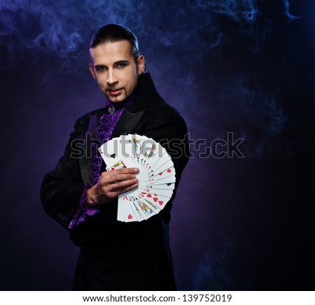 Young brunette magician in stage costume showing card tricks