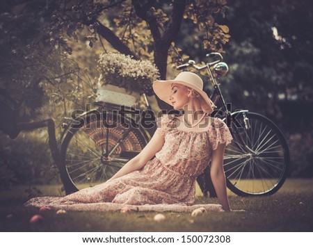 Beautiful dreaming blond retro woman with bicycle behind her