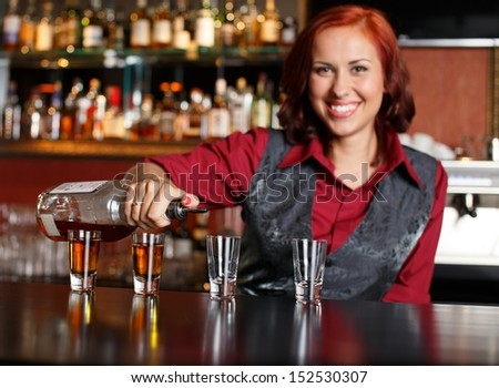 Beautiful redhead barmaid making shots