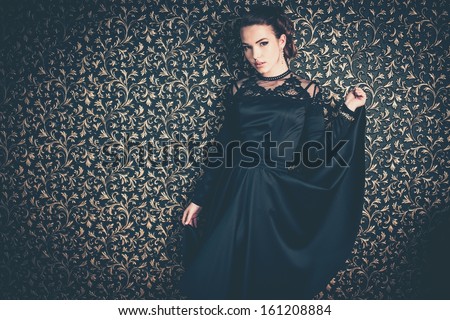 Beautiful young girl wearing black evening dress in luxury interior