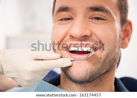 Handsome smiling man at doing checkup at dentist\'s surgery