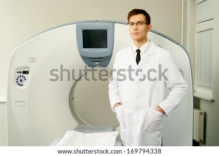Young doctor standing near computed tomography scanner in a hospital