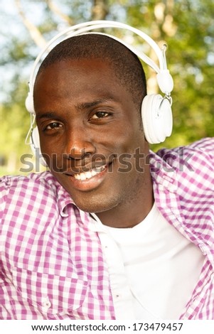 Positive young african american man listens music in a park